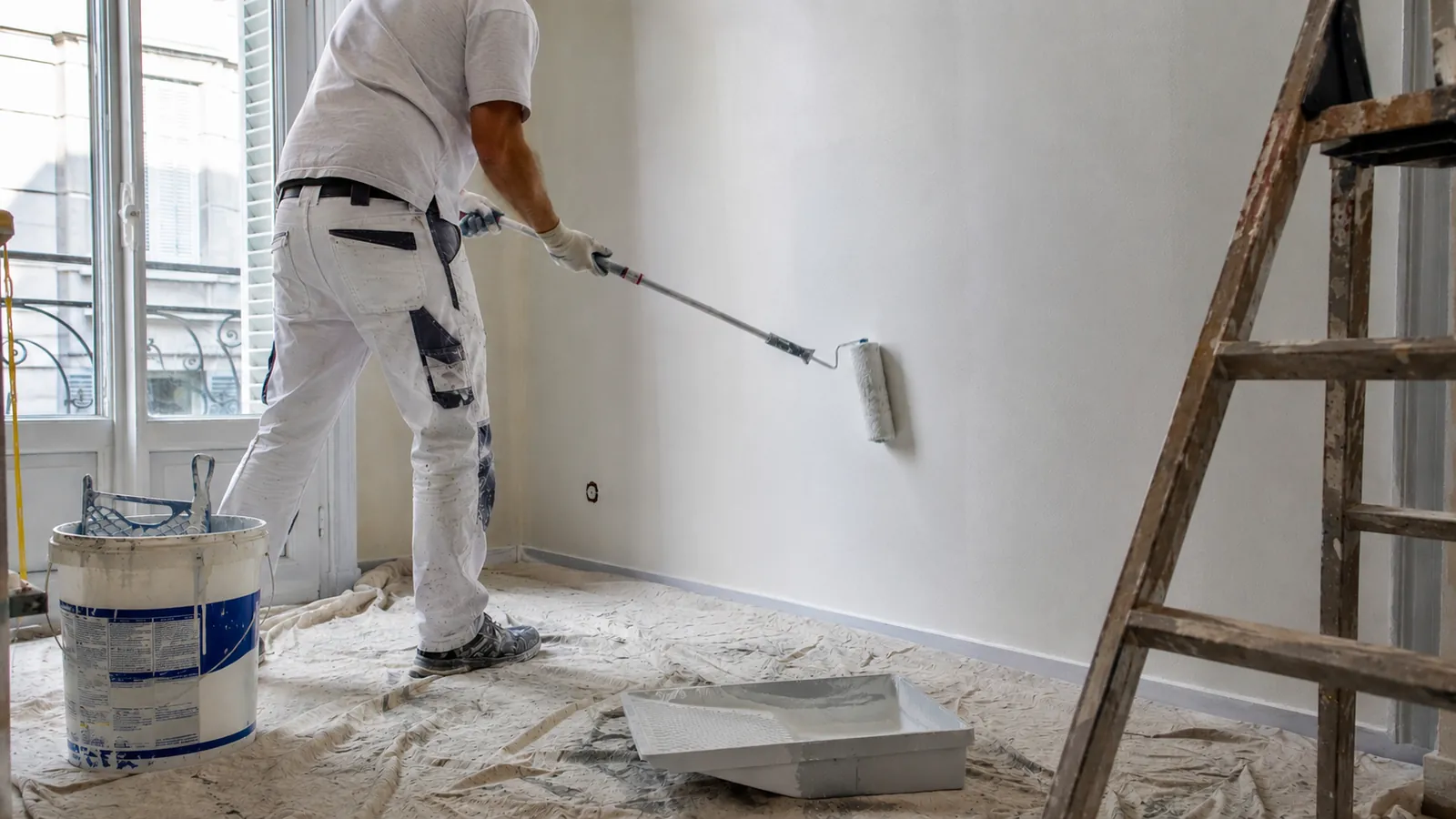 Peintre en bâtiment appliquant de la peinture au rouleau sur un chantier